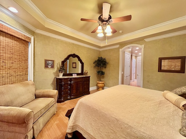 bedroom with ceiling fan, light wood-type flooring, ornamental molding, and a tray ceiling