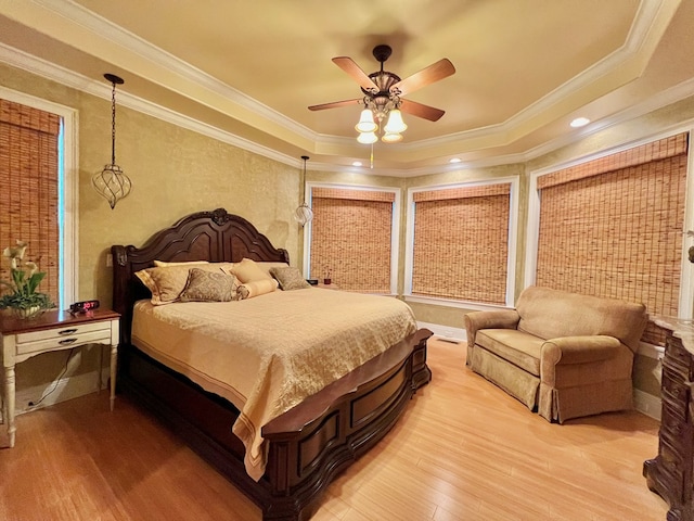 bedroom featuring light hardwood / wood-style floors, a raised ceiling, ceiling fan, and ornamental molding