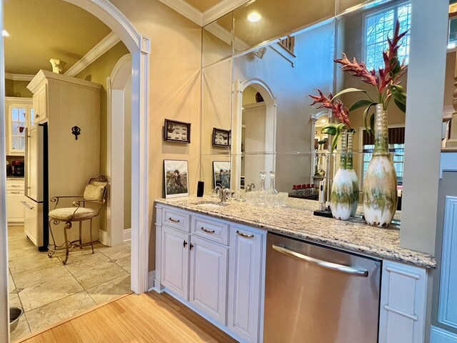 kitchen with light stone countertops, appliances with stainless steel finishes, ornamental molding, light hardwood / wood-style flooring, and white cabinets