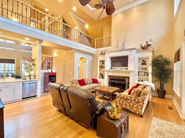 living room with ceiling fan, light hardwood / wood-style flooring, and a high ceiling