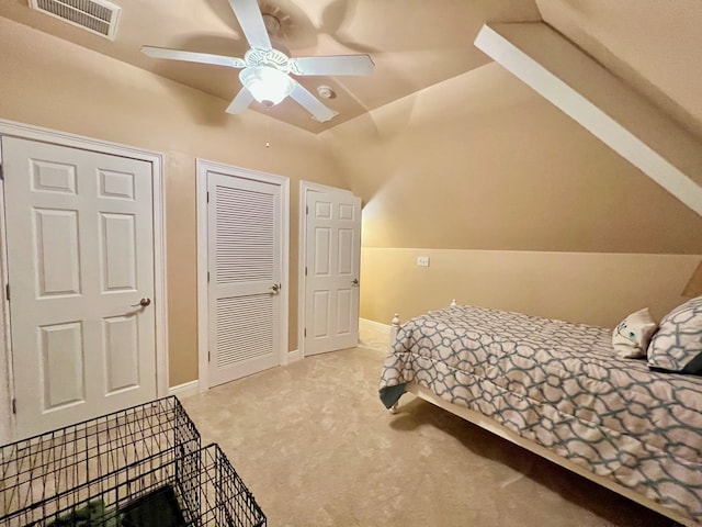 bedroom with multiple closets, ceiling fan, light carpet, and lofted ceiling