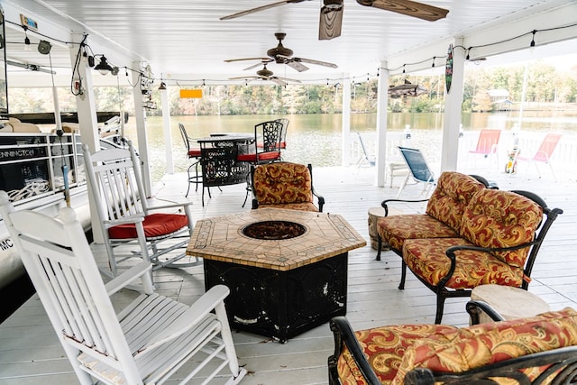 view of patio / terrace with ceiling fan, a water view, and an outdoor living space with a fire pit