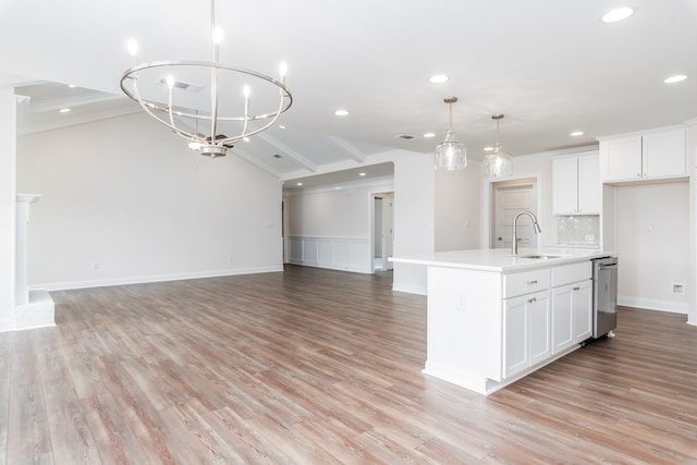 kitchen with white cabinetry, a kitchen island with sink, sink, and pendant lighting