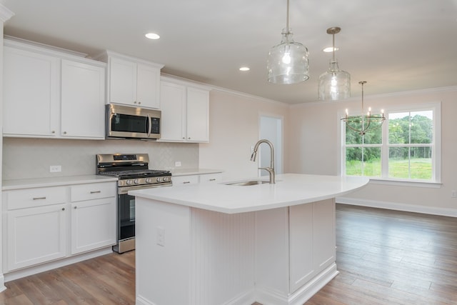 kitchen featuring stainless steel appliances, sink, pendant lighting, a center island with sink, and white cabinets