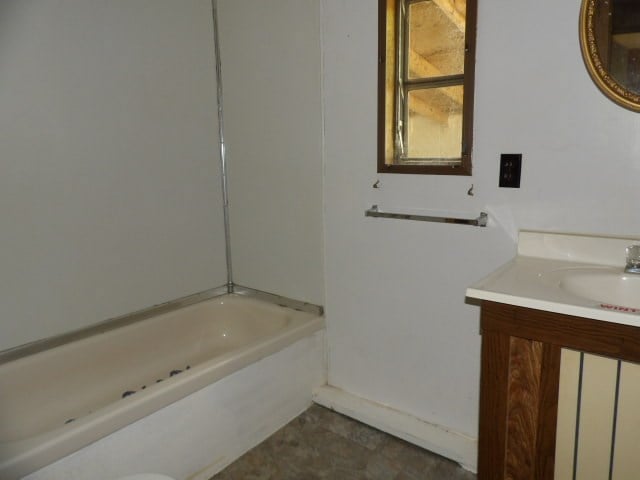 full bathroom with a bathing tub and vanity