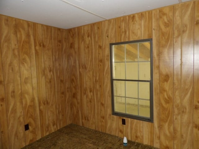 unfurnished room featuring wood walls