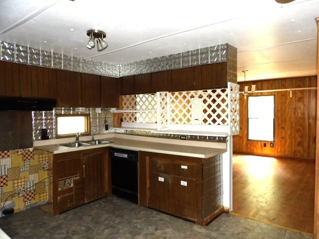 kitchen with black dishwasher, a sink, light countertops, and under cabinet range hood