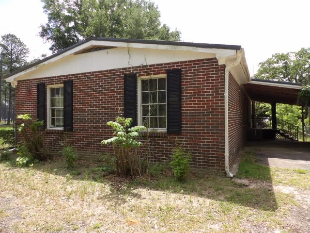 view of side of home featuring brick siding, driveway, and an attached carport