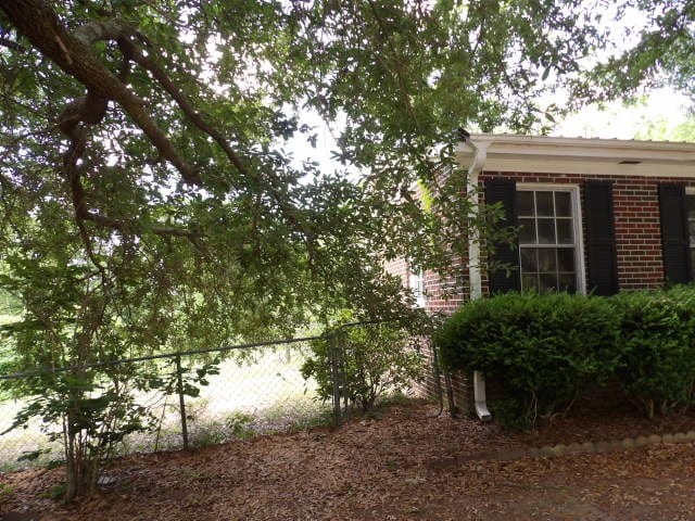 view of property exterior featuring brick siding and fence
