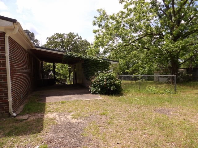 view of yard with driveway, fence, and a carport