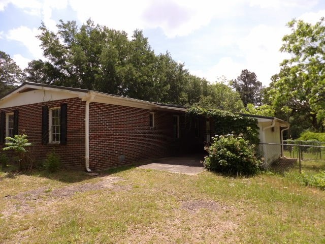 view of side of home with brick siding, fence, and a lawn