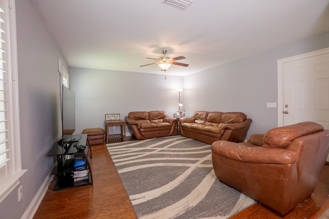 living room featuring a ceiling fan, baseboards, visible vents, and wood finished floors