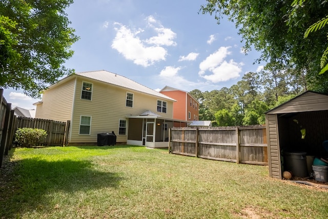 rear view of house with a sunroom, a fenced backyard, a lawn, and metal roof