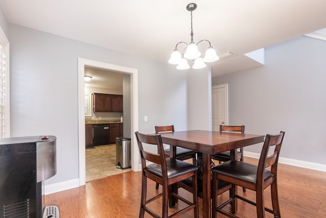 dining room featuring baseboards, a chandelier, and light wood finished floors