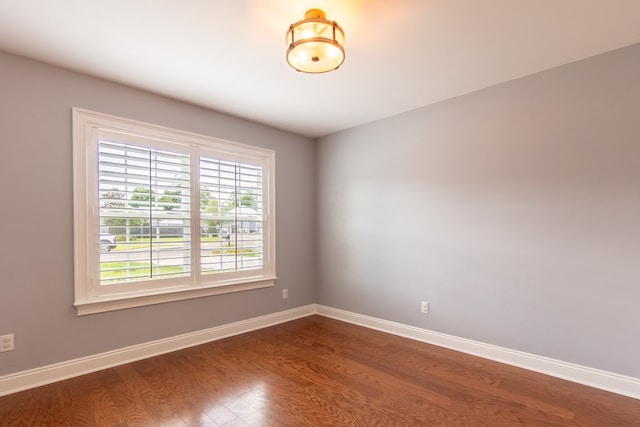 empty room featuring baseboards and dark wood-style floors