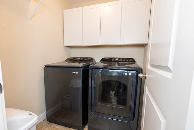 clothes washing area featuring baseboards, cabinet space, light tile patterned flooring, and washer and dryer
