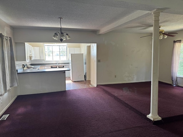 kitchen with a textured ceiling, a peninsula, visible vents, and a healthy amount of sunlight