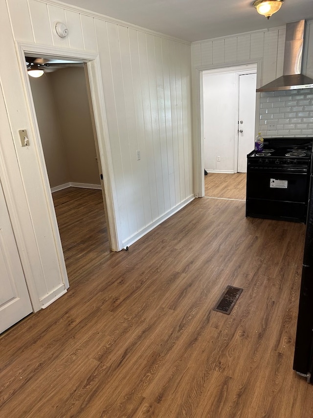 kitchen featuring white cabinetry, wall chimney exhaust hood, dark wood-type flooring, tasteful backsplash, and black range with gas cooktop