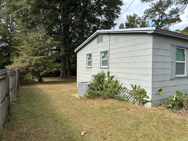 view of side of home with a lawn and central AC