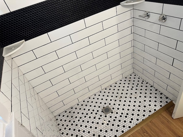 room details with wood-type flooring and tiled shower