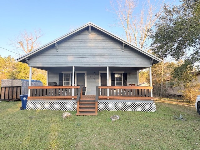 rear view of property with covered porch and a yard