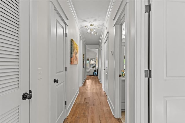 hall featuring baseboards, ornamental molding, and light wood-type flooring