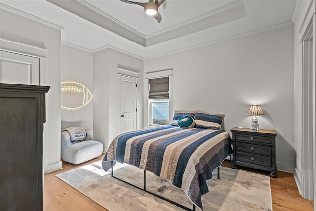 bedroom featuring crown molding, ceiling fan, wood finished floors, and a tray ceiling