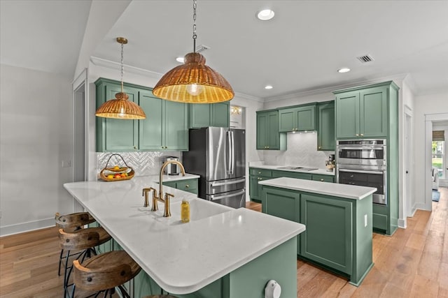 kitchen with decorative backsplash, green cabinetry, stainless steel appliances, and a peninsula