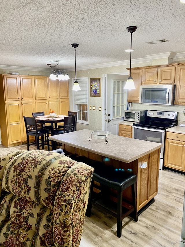 kitchen with crown molding, a kitchen island, hanging light fixtures, and appliances with stainless steel finishes