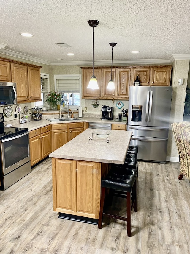 kitchen featuring light wood-type flooring, a center island, stainless steel appliances, and sink