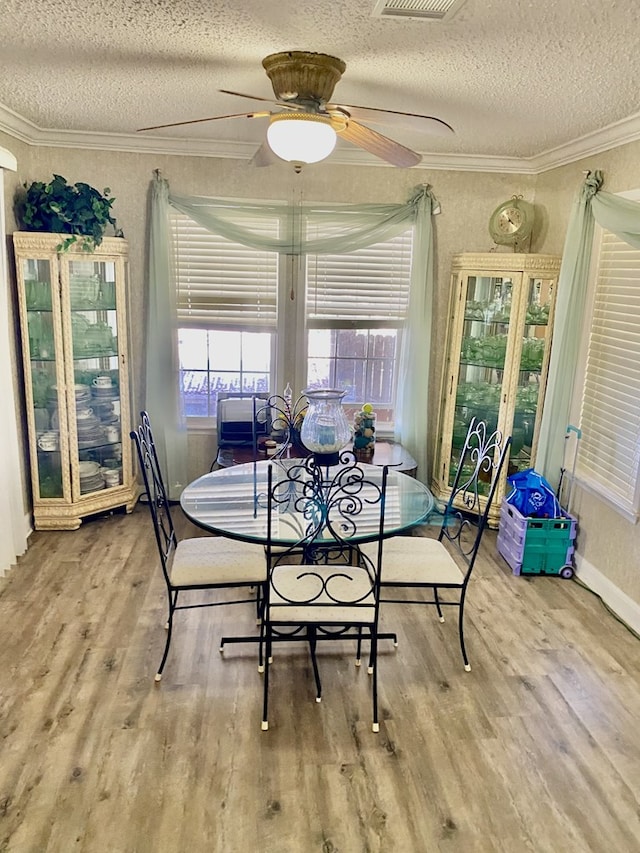 dining area featuring crown molding, wood-type flooring, and a textured ceiling