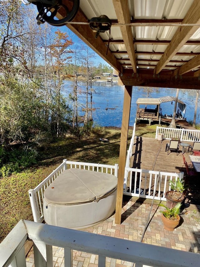 wooden terrace with a patio area, a water view, and a hot tub