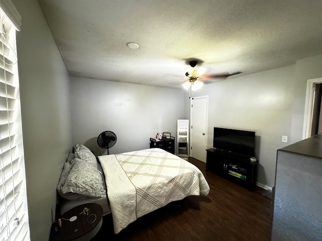 bedroom with a textured ceiling, ceiling fan, and dark hardwood / wood-style floors