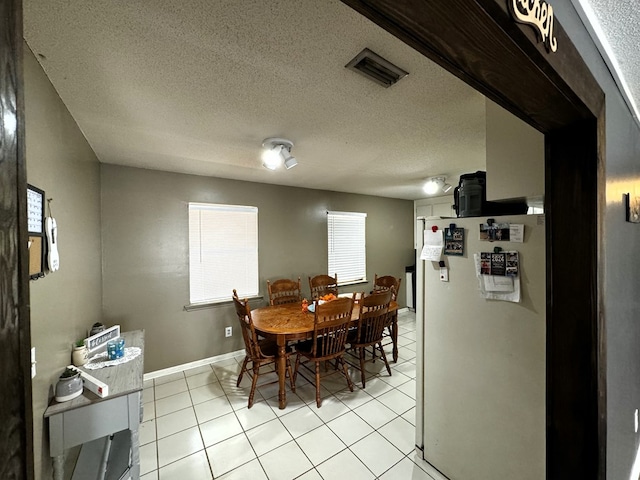 dining space with light tile patterned flooring and a textured ceiling