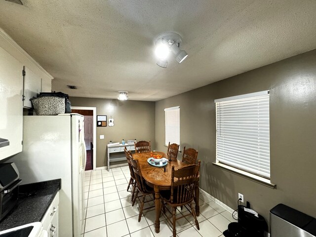 tiled dining space with a textured ceiling