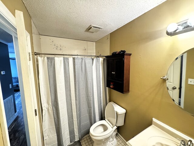 bathroom featuring tile patterned floors, a shower with curtain, sink, toilet, and a textured ceiling