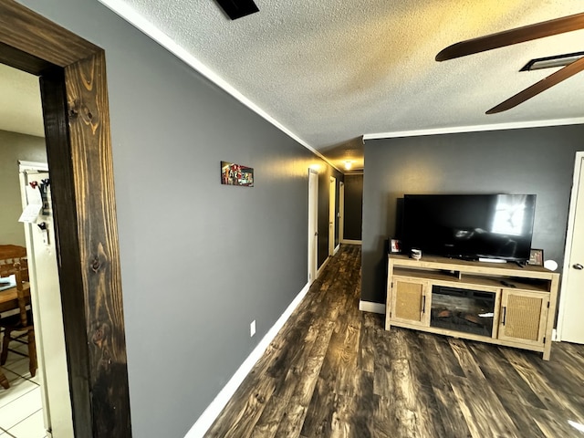 living room with crown molding, ceiling fan, dark wood-type flooring, and a textured ceiling