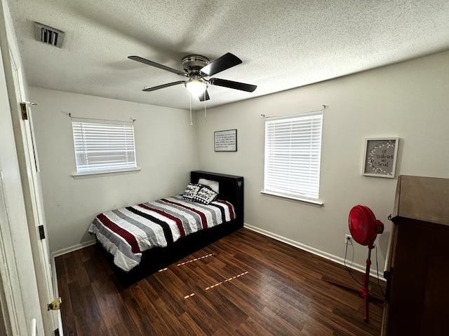 bedroom with ceiling fan, dark hardwood / wood-style flooring, and a textured ceiling