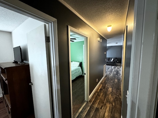 hallway with dark hardwood / wood-style flooring, ornamental molding, and a textured ceiling