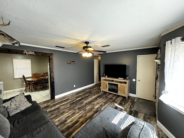 living room with hardwood / wood-style flooring, ceiling fan, crown molding, and a textured ceiling