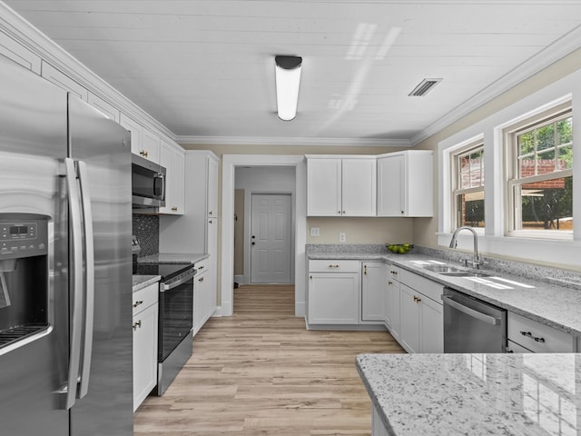 203 E Mckinnon St, New Brockton, AL 36351 - kitchen featuring appliances with stainless steel finishes, crown molding, white cabinets, light stone countertops, and light wood-type flooring