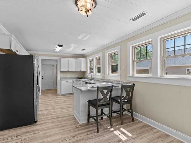 203 E Mckinnon St, New Brockton, AL 36351 - kitchen featuring freestanding refrigerator, a peninsula, light wood-type flooring, ornamental molding, and white cabinetry