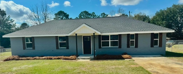 ranch-style home with a shingled roof, a front yard, brick siding, and fence