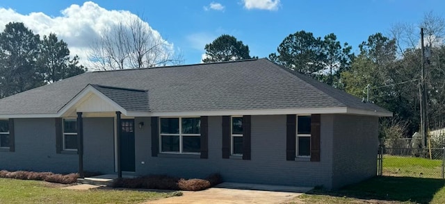 ranch-style home featuring roof with shingles, fence, and brick siding