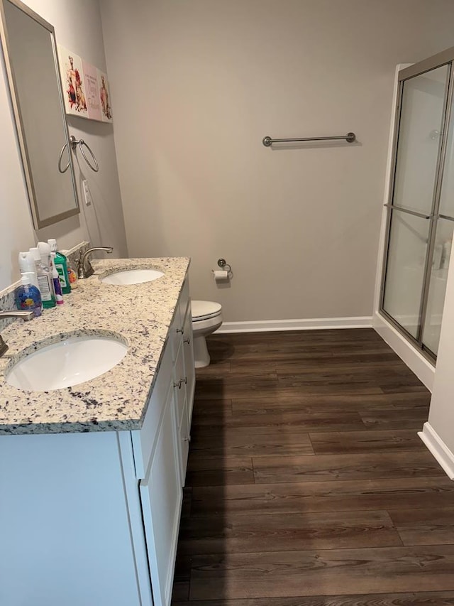 bathroom with toilet, wood-type flooring, vanity, and a shower with door