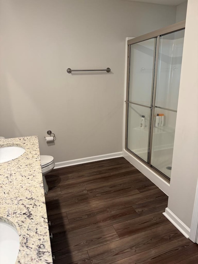 bathroom featuring wood-type flooring, an enclosed shower, vanity, and toilet