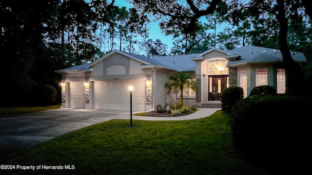 ranch-style house with a garage and a yard