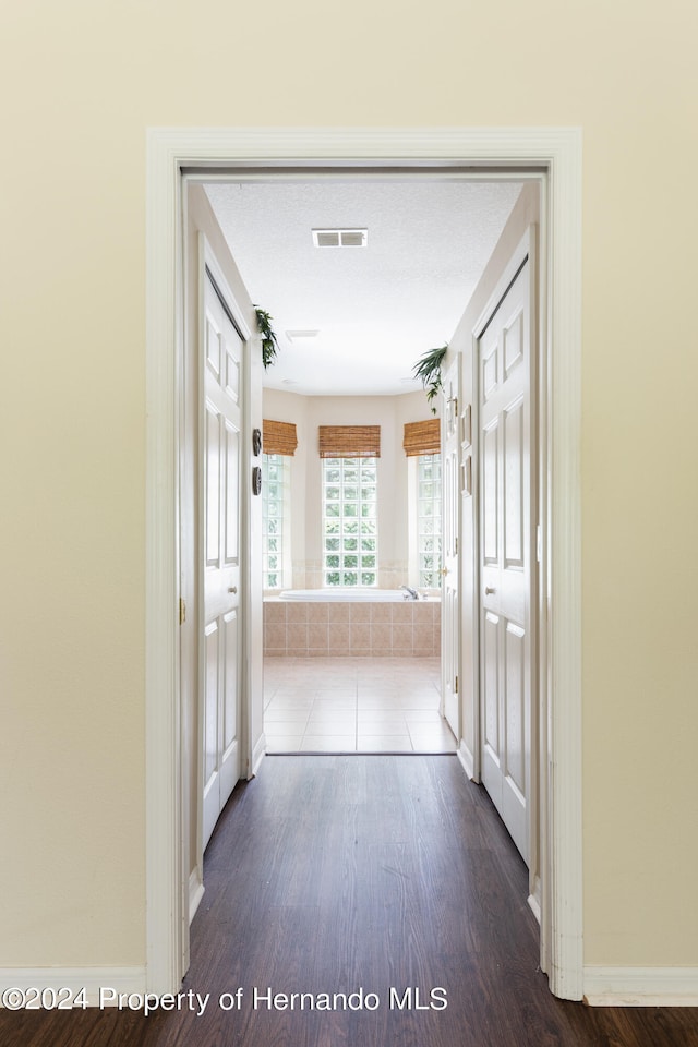 corridor with wood-type flooring and a textured ceiling