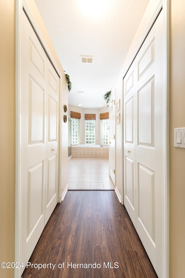 hallway with hardwood / wood-style flooring and a textured ceiling