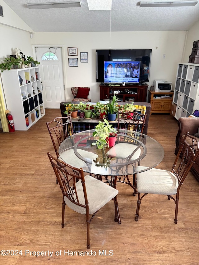 dining area with a textured ceiling and light hardwood / wood-style flooring